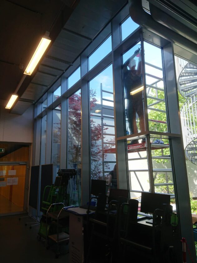 Monteur bei der Installation der Sonnenschutzfolie auf große Fensterscheiben